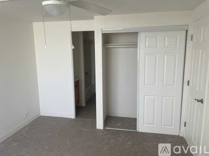 A room with a white door and a ceiling fan.
