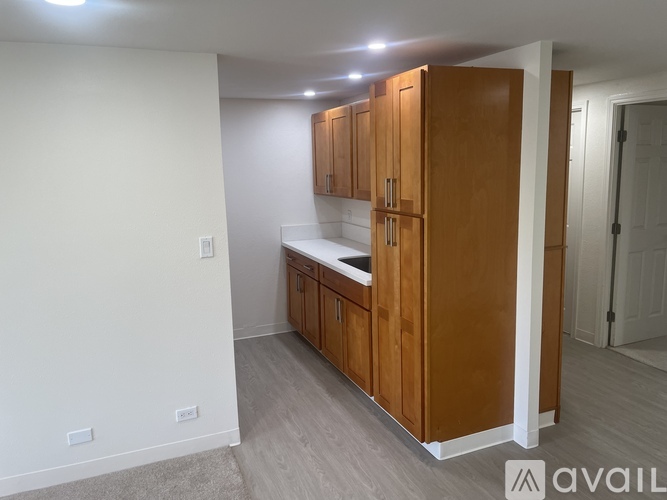 A kitchen area with wooden cabinets and a white wall.