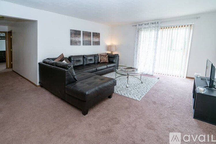 A living room with a black leather sofa and a television.