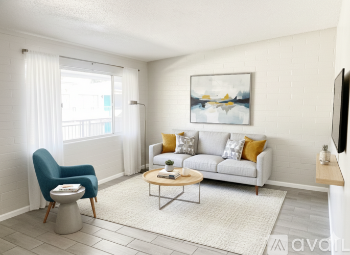 A living room with a blue chair, a white couch, and a painting on the wall.