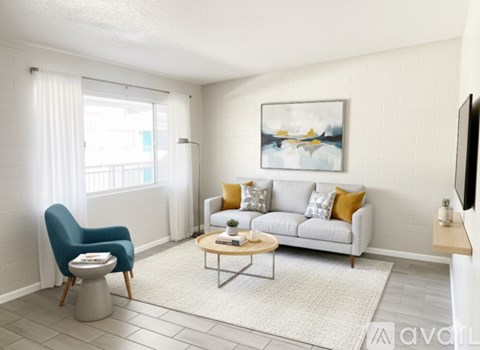 A living room with a blue chair, a white couch, and a painting on the wall.