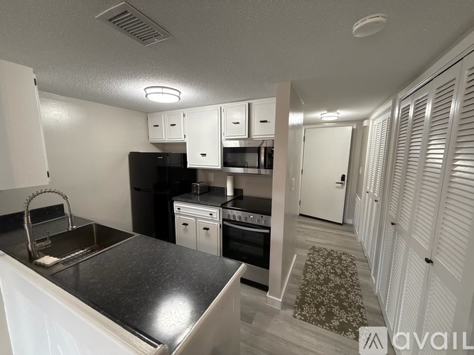 A kitchen with black appliances and white cabinets.