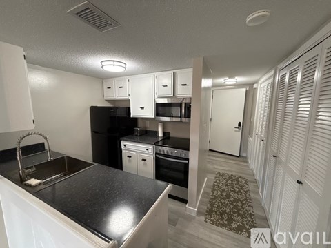 A kitchen with black appliances and white cabinets.