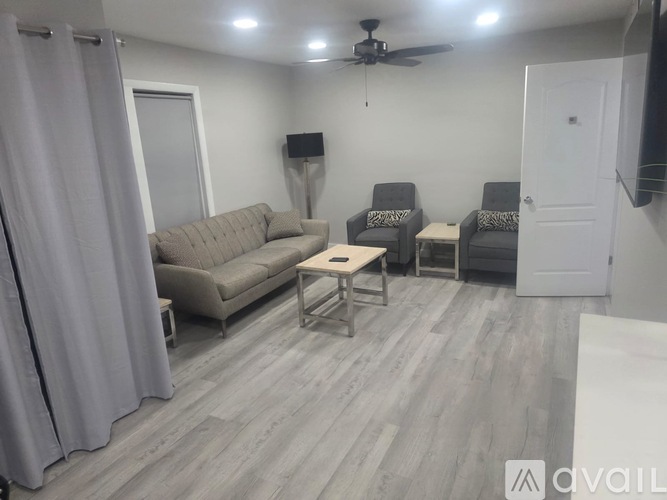 A living room with a grey sofa, two chairs and a coffee table.