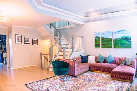 A living room with a pink couch and a green chair.