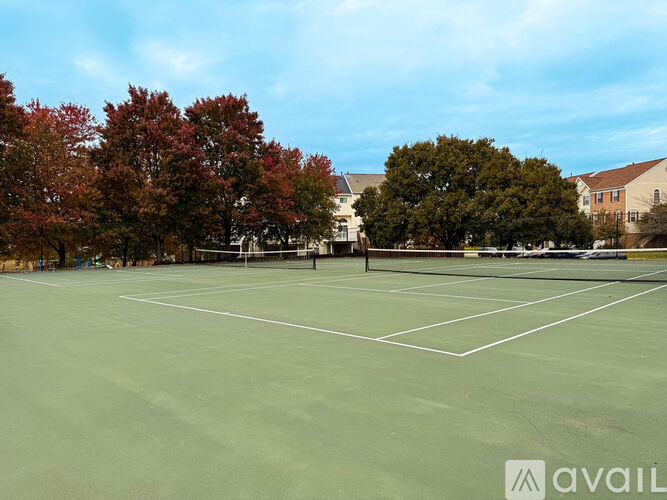 A tennis court surrounded by trees and buildings.