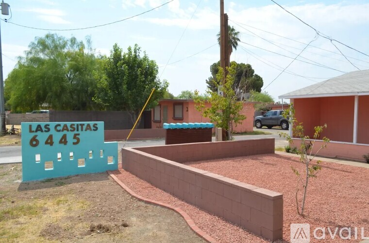 A sign that says "LAS CASITAS 6445" is in front of a brick wall.