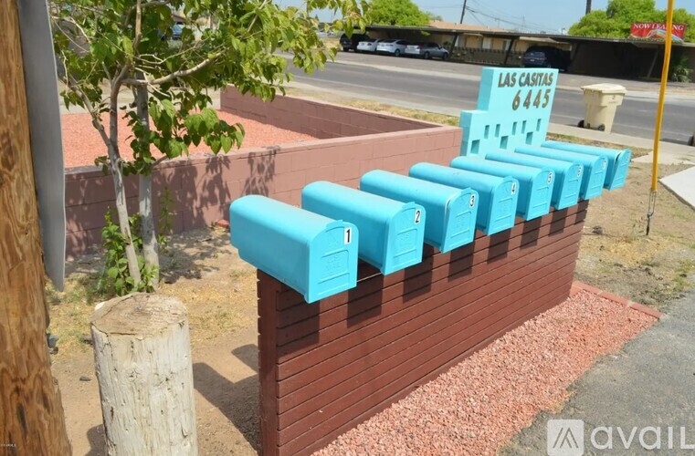 A row of blue mailboxes are on a brick wall.