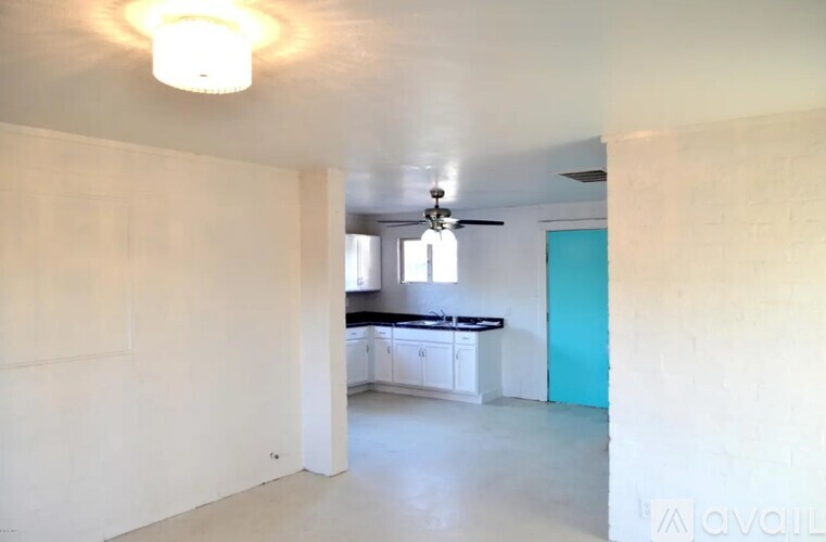 A room with a ceiling fan and a kitchen area with a counter and cabinets.