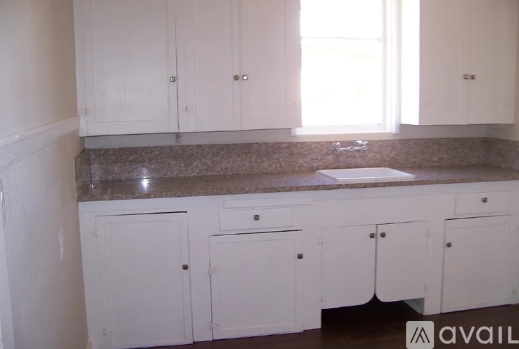 A kitchen with white cabinets and a granite countertop.