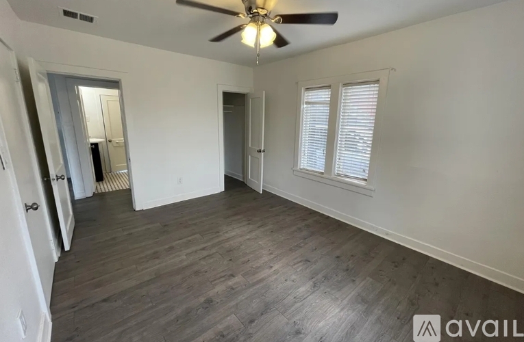 A spacious room with a ceiling fan and wooden flooring.