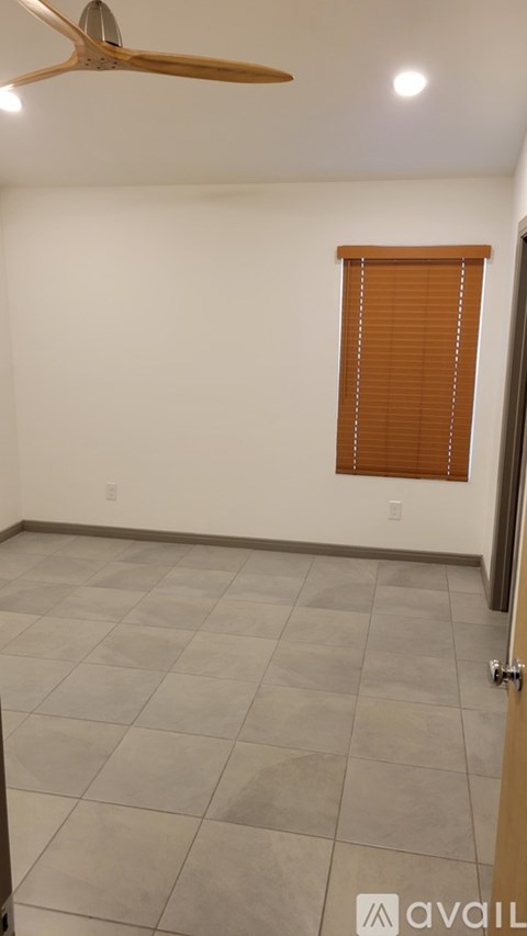 A room with a ceiling fan and a window with blinds.