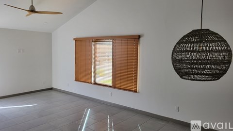 A room with a ceiling fan, a window with blinds, and a hanging light fixture.