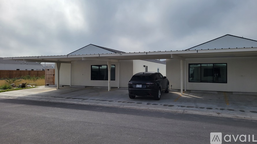 A black car is parked in front of a building with a white and beige exterior.