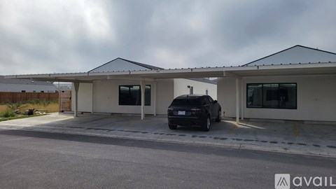 A black car is parked in front of a building with a white and beige exterior.