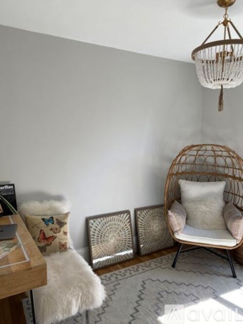 A chair with a white cushion is placed in front of three decorative wall hangings.