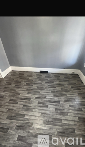 A room with a wooden floor and a grey wall.