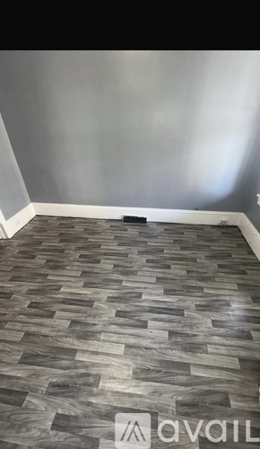 A room with a wooden floor and a grey wall.