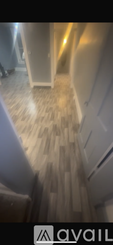 A hallway with wooden flooring and a white door.
