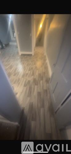 A hallway with wooden flooring and a white door.