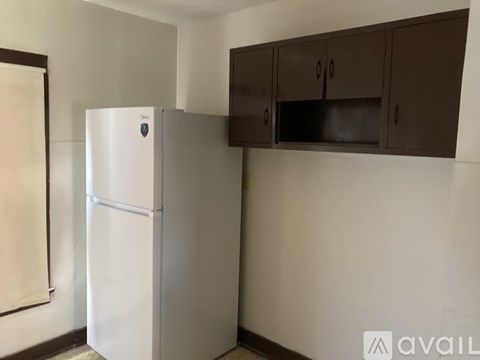 A white refrigerator is in a kitchen with brown cabinets.