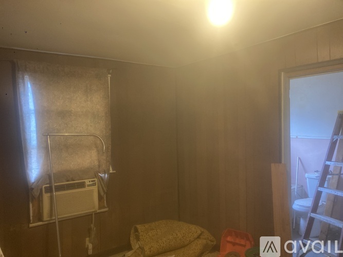 A room with a bed, a chair, and a window with a curtain.