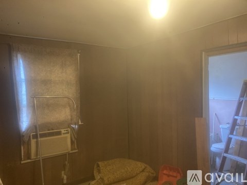 A room with a bed, a chair, and a window with a curtain.