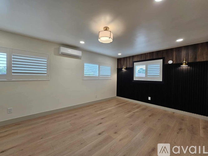 A room with wooden flooring and a window with blinds.