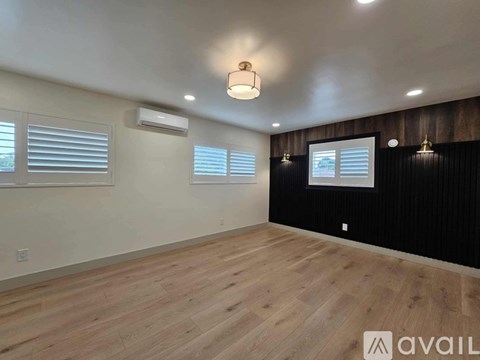 A room with wooden flooring and a window with blinds.