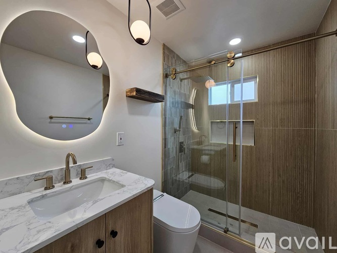 A bathroom with a marble countertop and a round mirror.
