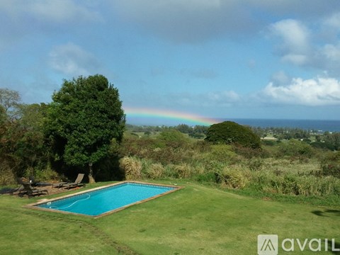 A pool surrounded by green grass with a rainbow in the background.