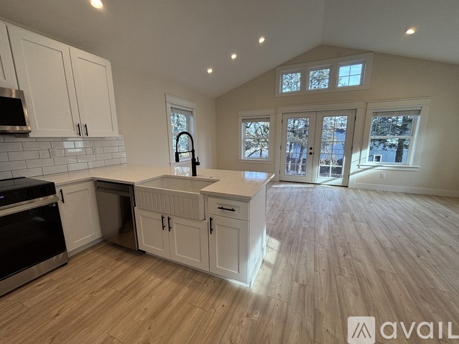 A kitchen with wooden floors and white cabinets.