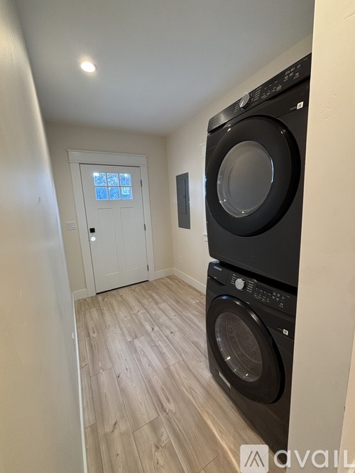 A black washing machine and dryer in a small laundry room.