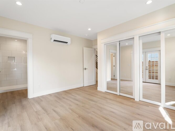 A spacious room with wooden flooring and a large window.