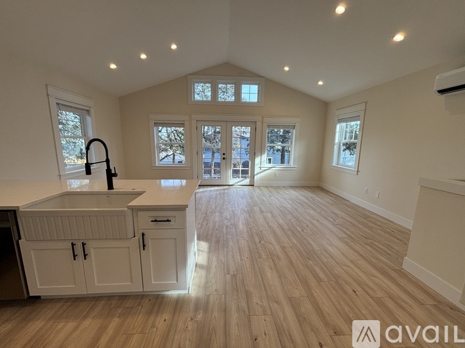 A kitchen with white cabinets and a wooden floor.