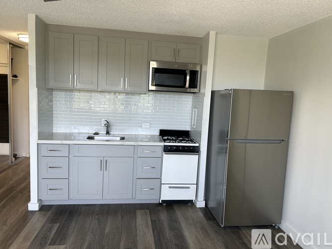 A kitchen with a refrigerator, sink, and cabinets.