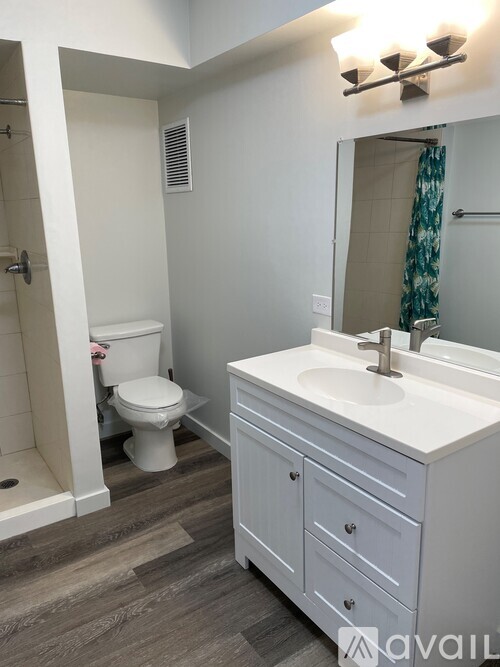 A bathroom with a toilet, sink, and mirror.