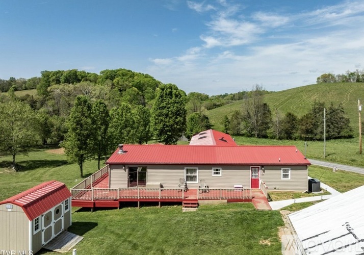 A house with a red roof is surrounded by greenery.