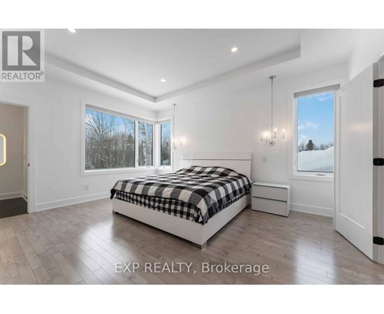 A bedroom with a large bed and a view of the outdoors through the window.
