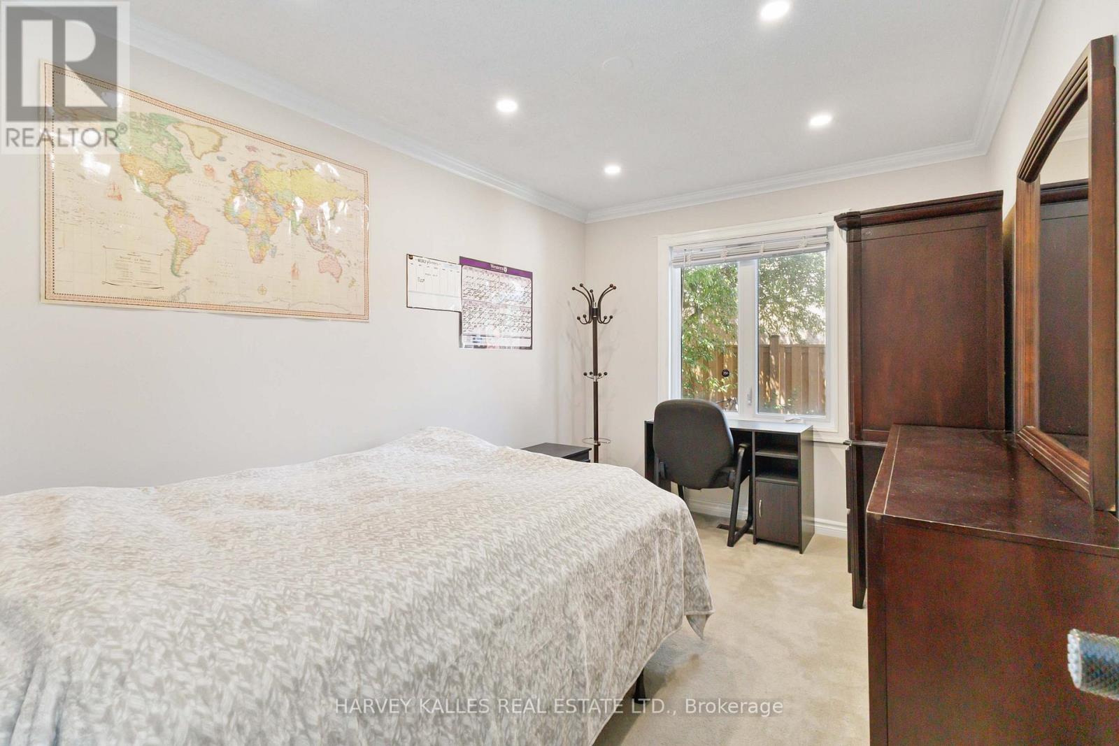 A bedroom with a world map on the wall and a bed with a white comforter.