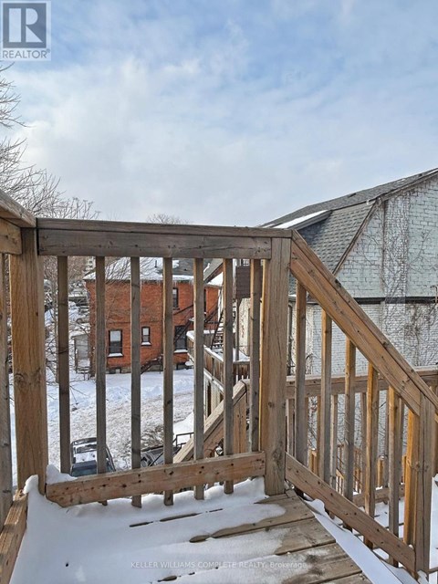 A wooden deck with snow on the ground and a building in the background.