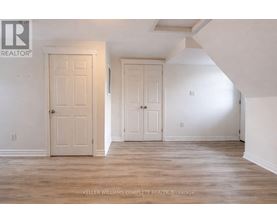 A room with two doors and a brokerage sign.