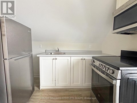 A kitchen with white cabinets and a stainless steel refrigerator.