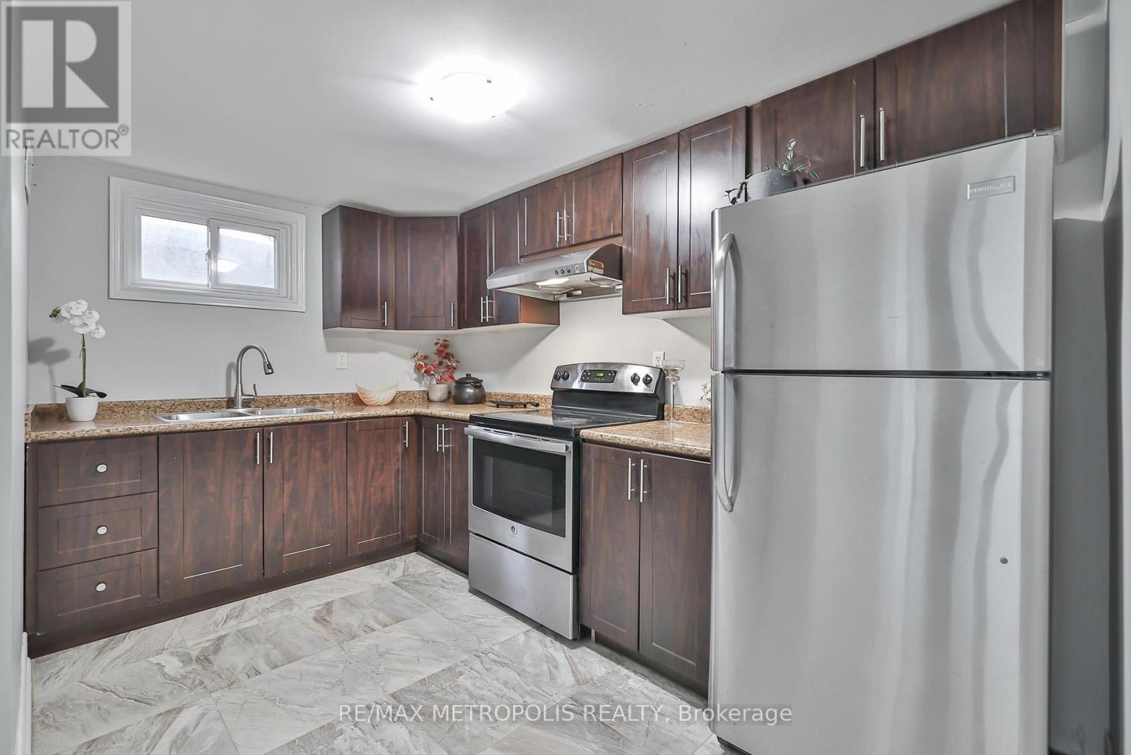 A kitchen with a refrigerator, microwave, oven, and sink.