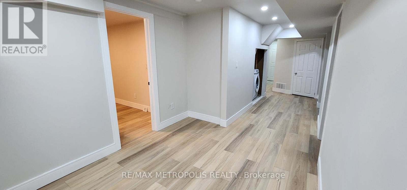 A hallway with wood flooring and white walls.