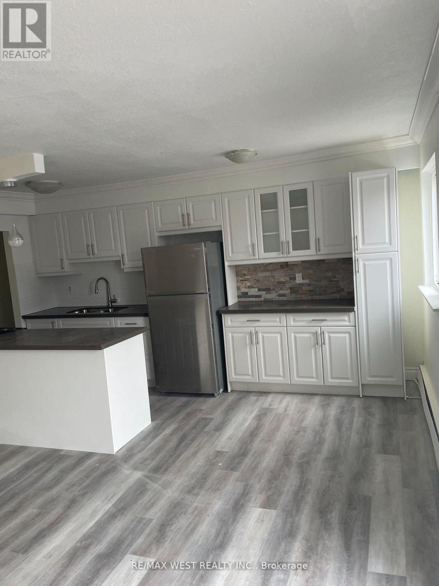 A kitchen with white cabinets and a grey refrigerator.