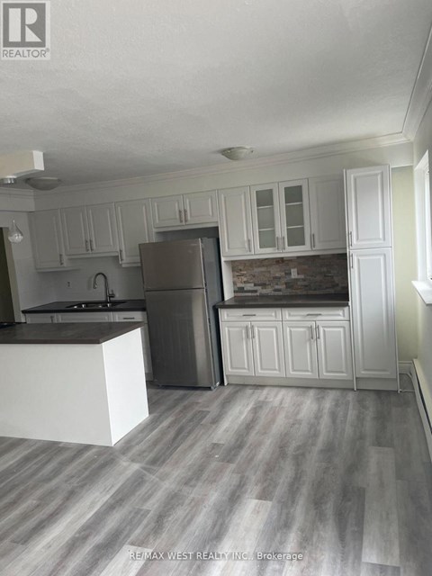 A kitchen with white cabinets and a grey refrigerator.