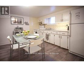 A kitchen with a table set for two with a brokerage sign in the corner.