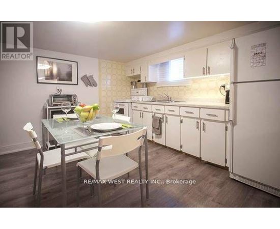 A kitchen with a table set for two with a brokerage sign in the corner.