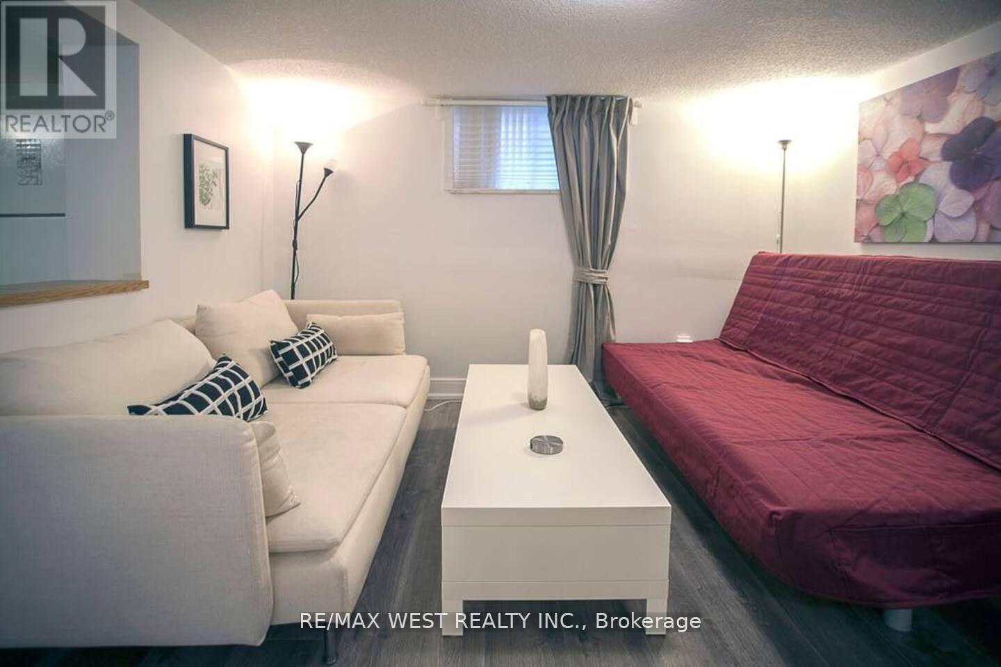 A living room with a white couch and a red bed.